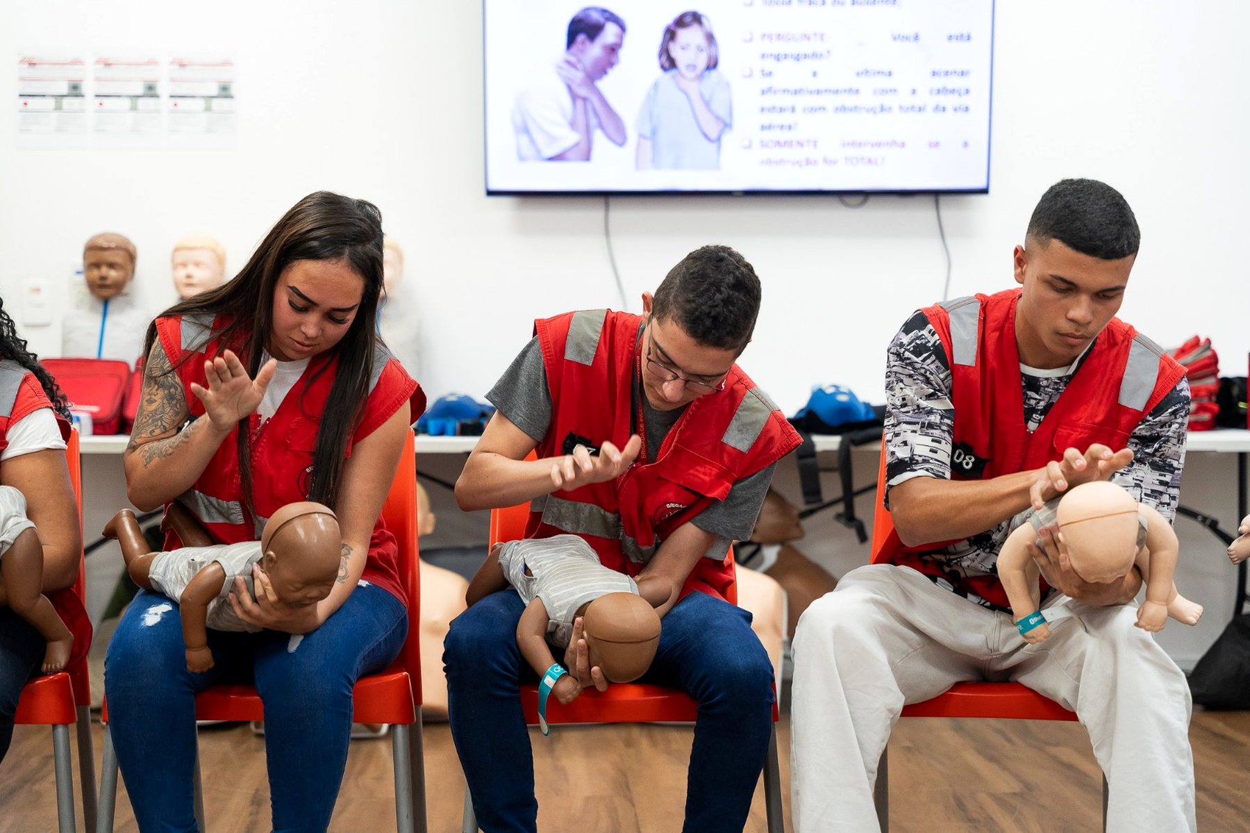 Alunos praticando primeiros socorros em manequins infantis