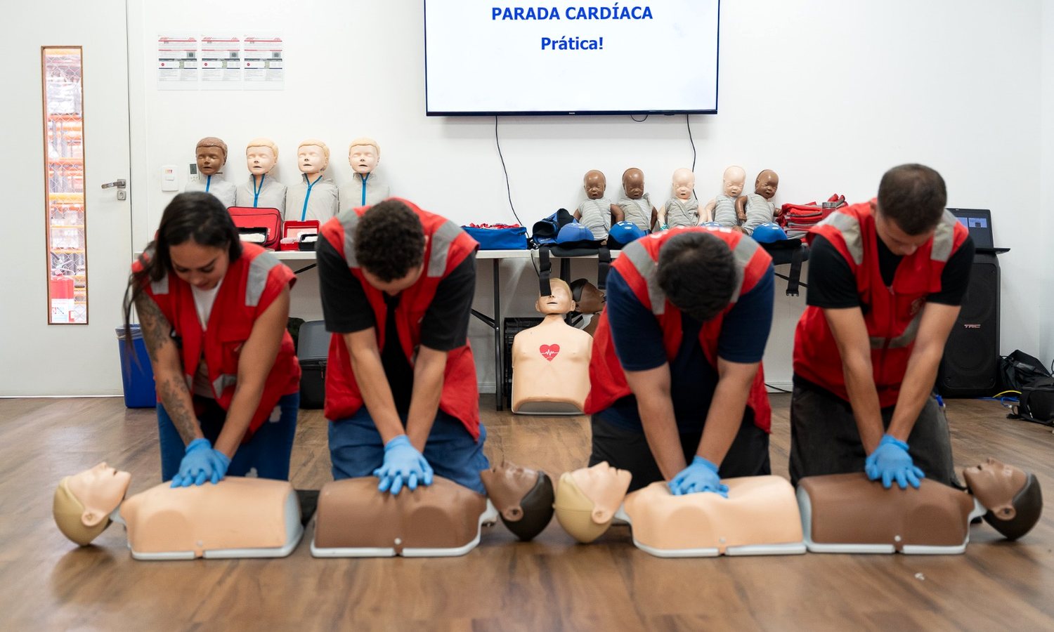 Turma praticando compressões torácicas em manequins de treinamento